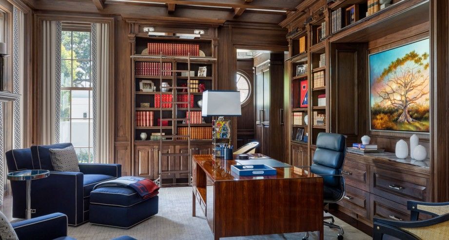 Library with floor to ceiling bookcases, nickel detailing, and an antique desk.