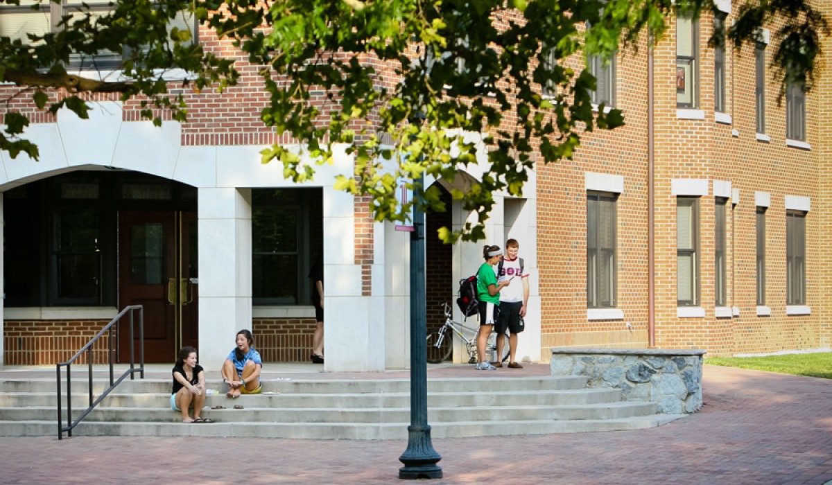 Students outside of the building - two sitting on steps