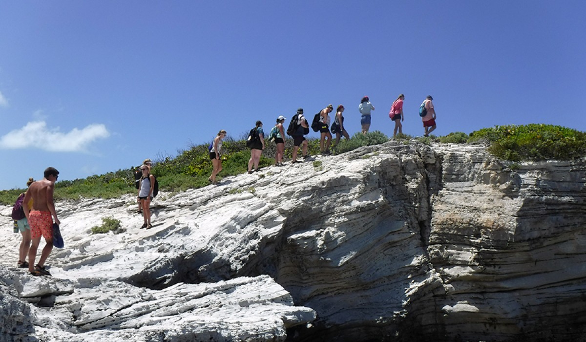The group hikes up a rocky slope on Cut Cay